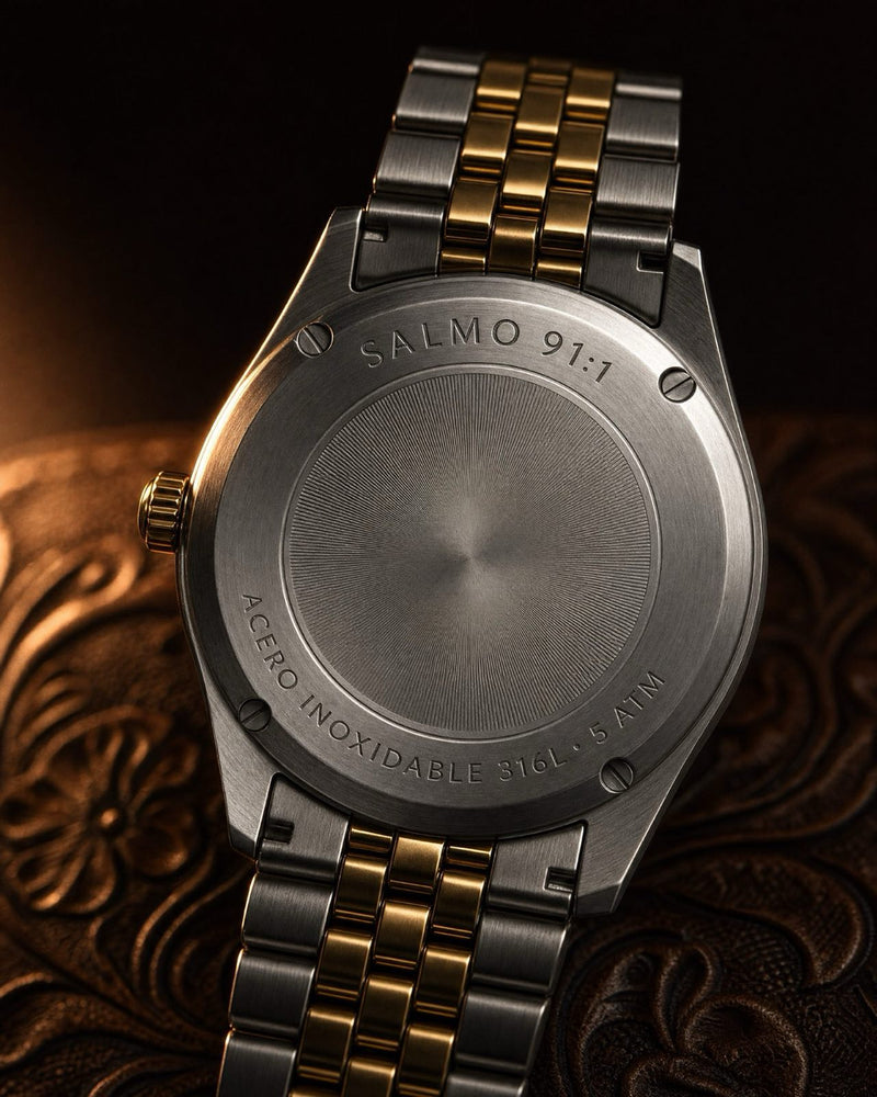 The engraved steel caseback of a two-tone watch on tooled leather